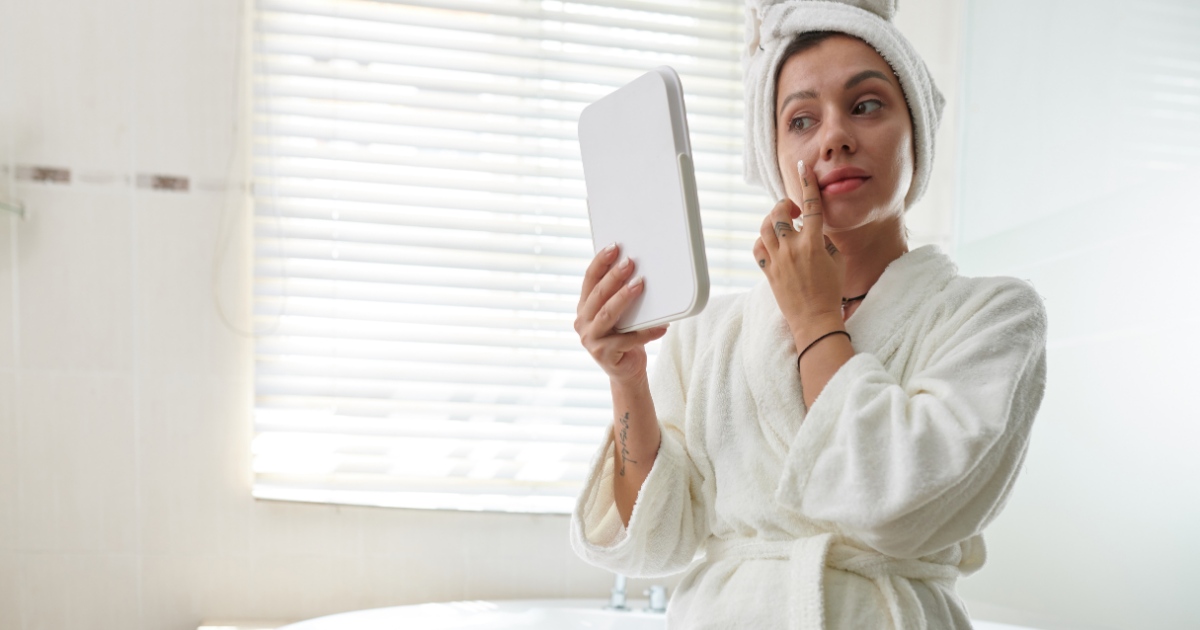 a woman examining her skin in the mirror