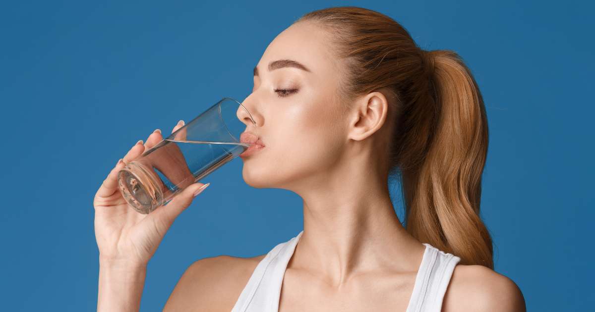 A beautiful woman drinking a glass of water.