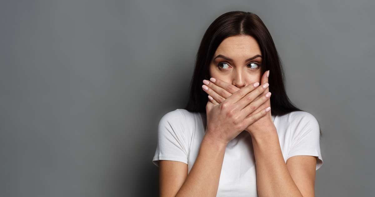 A woman hiding her lips with her hands.