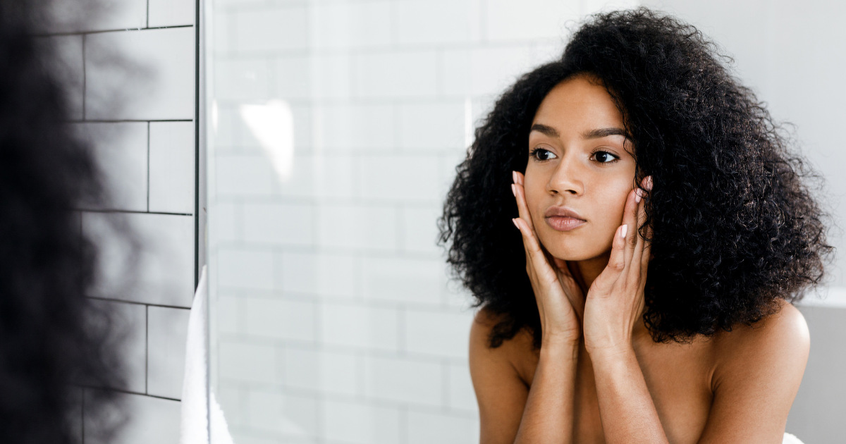 A curly-haired woman looking herself in the mirror