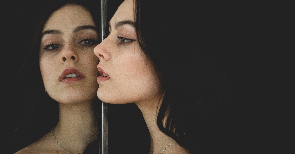 woman looking at their lips in the mirror